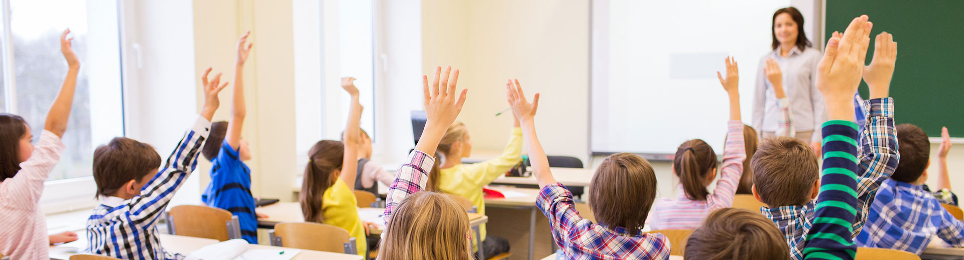 Photo of students raising their hands in a classroom